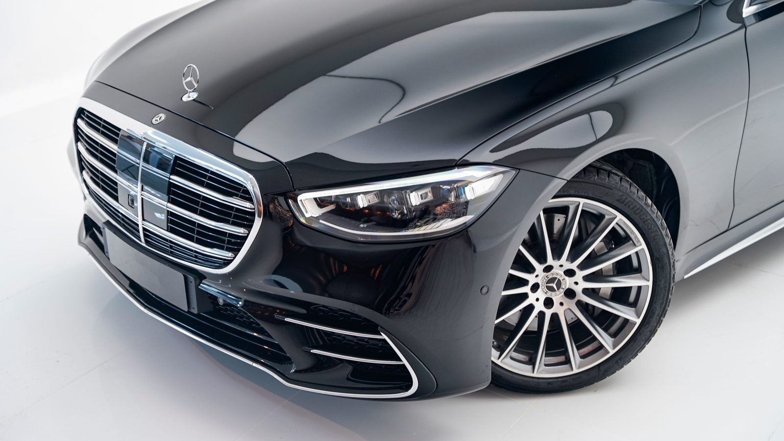 Long-wheelbase luxury sedan at night outside a glass office tower
