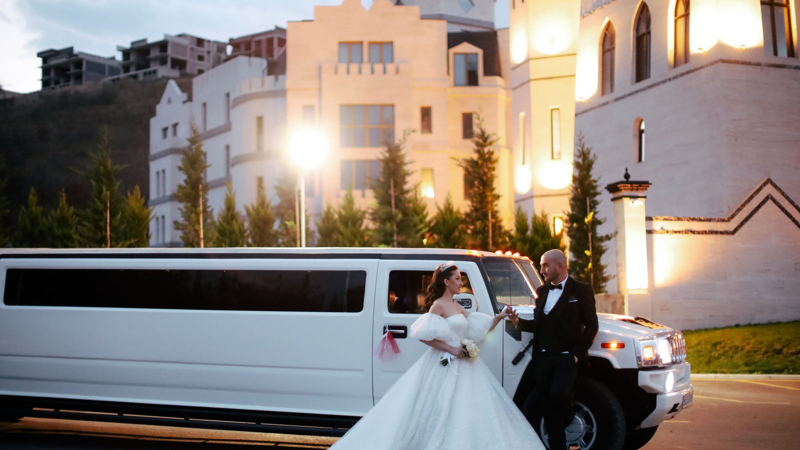 White stretch limousine outside a wedding venue at dusk